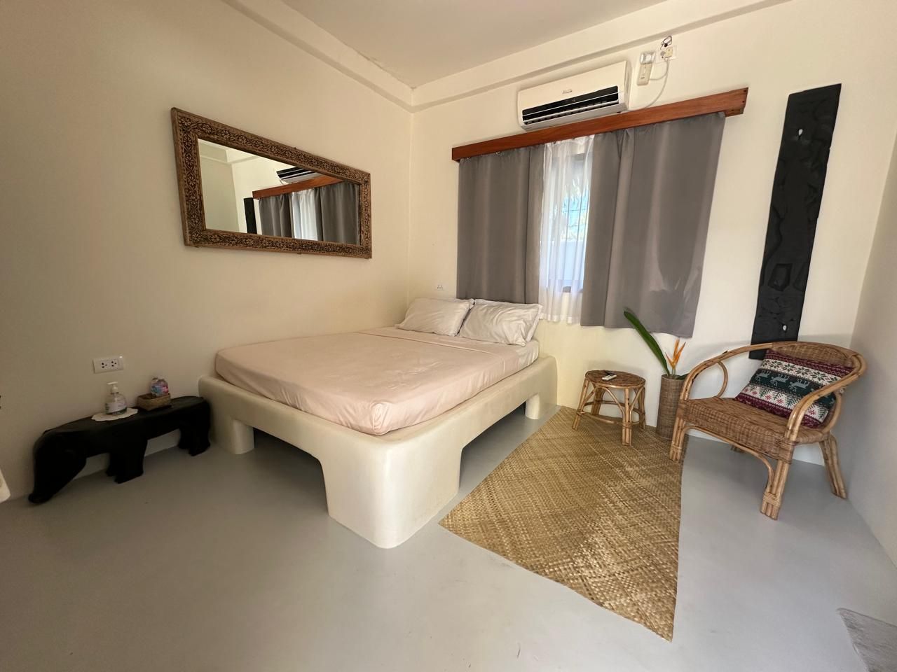 A bedroom with a bed , chair , mirror and air conditioner.