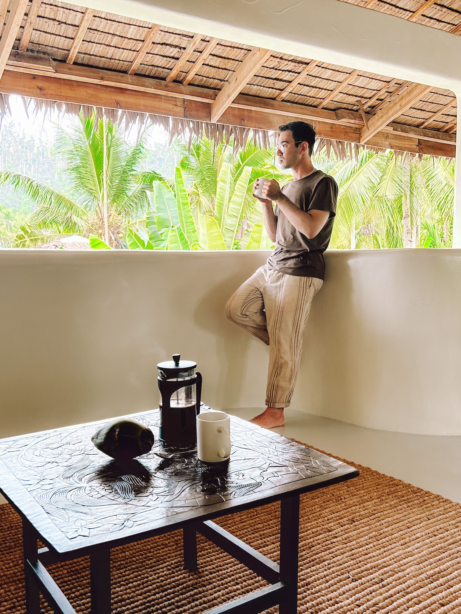A man is leaning against a wall next to a coffee table.