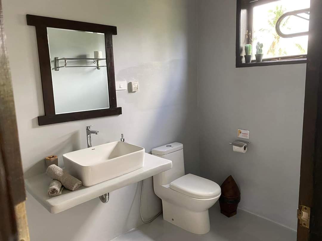 A bathroom with a sink , toilet , mirror and window.