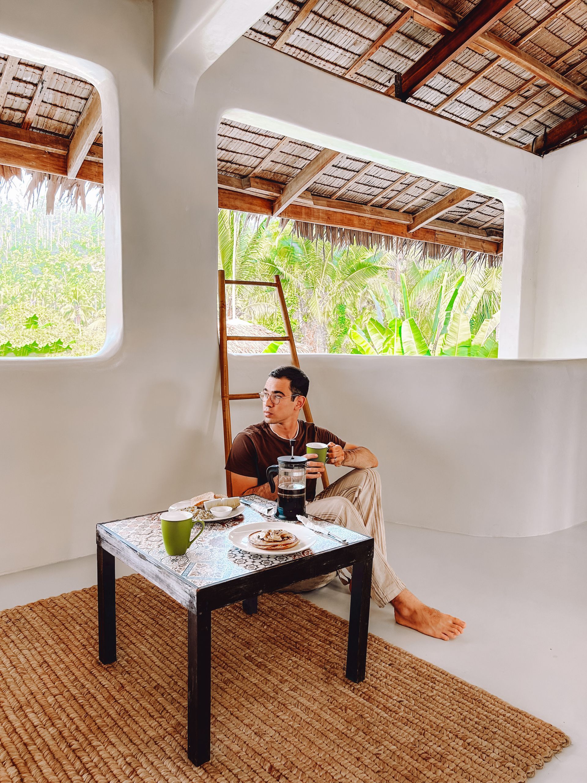A man is sitting on a porch drinking coffee.