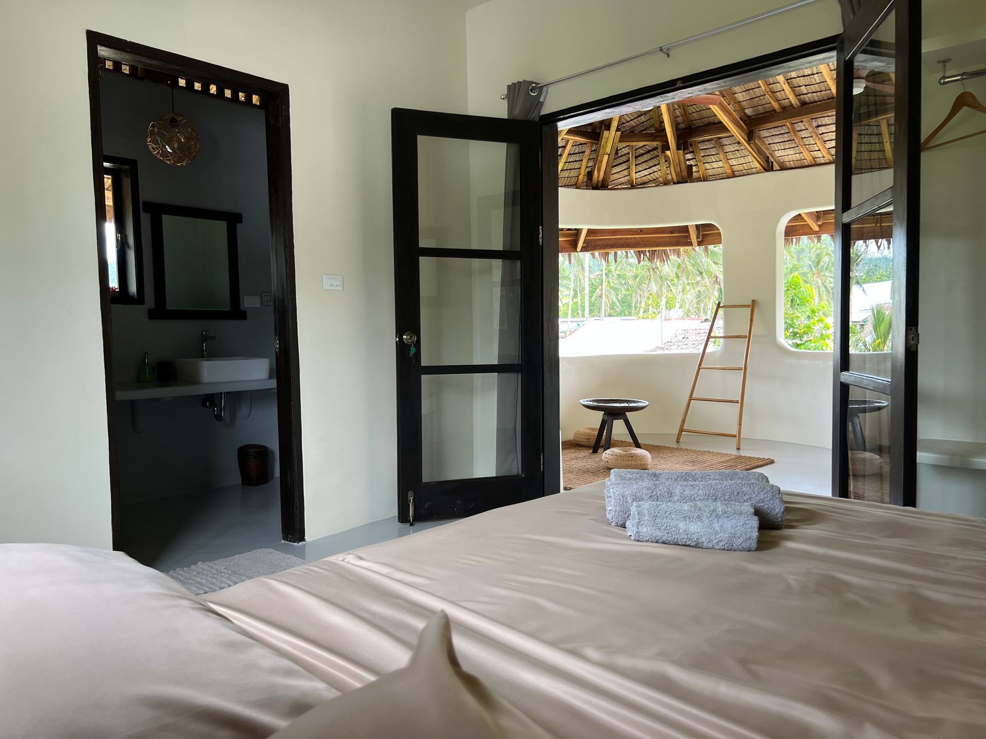 A bedroom with a bed , a bathroom and a balcony.