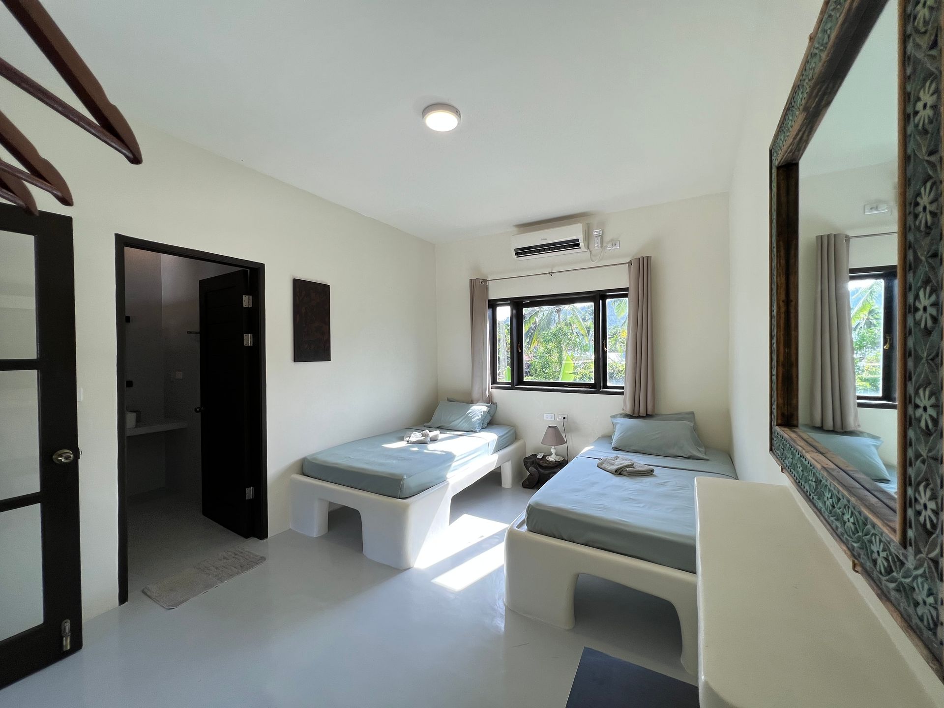 A bedroom with two beds and a mirror