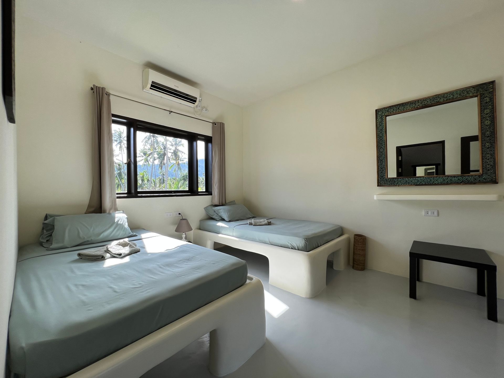 A bedroom with two beds and a mirror on the wall.