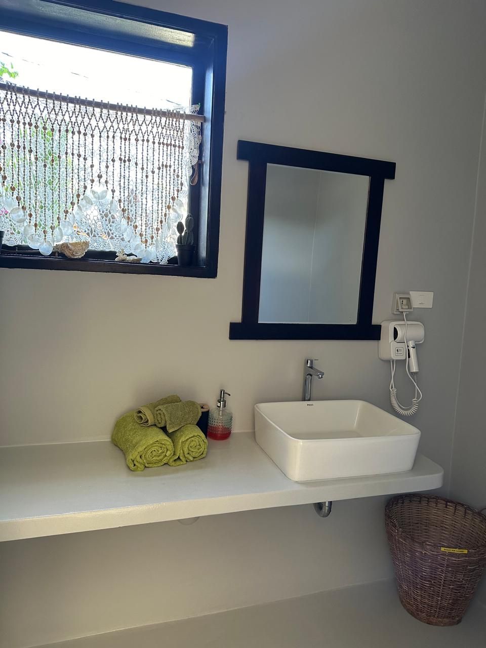 A bathroom with a sink , mirror and window