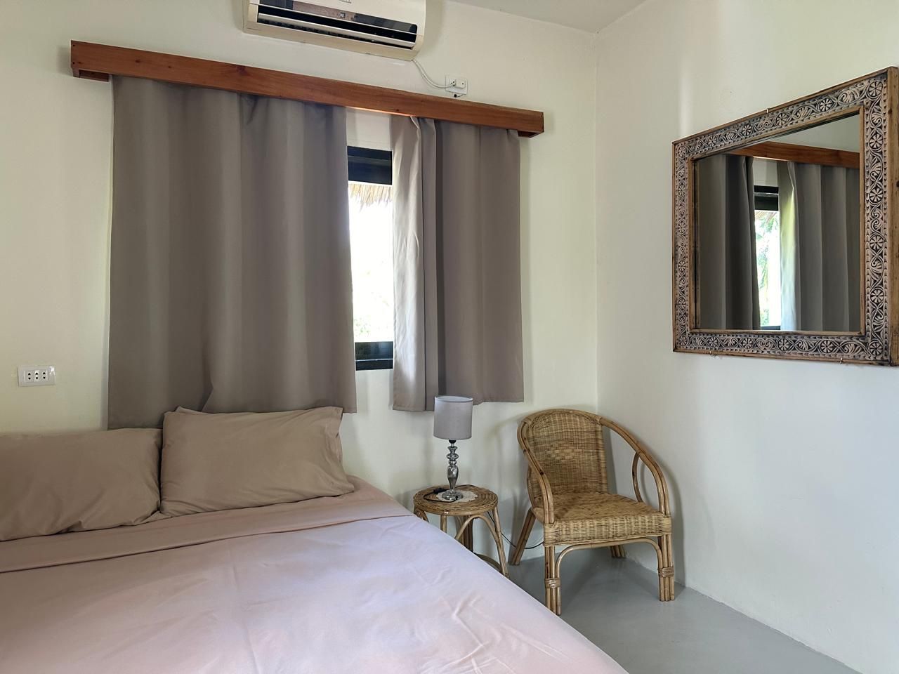 A bedroom with a bed , chair , mirror and air conditioner.