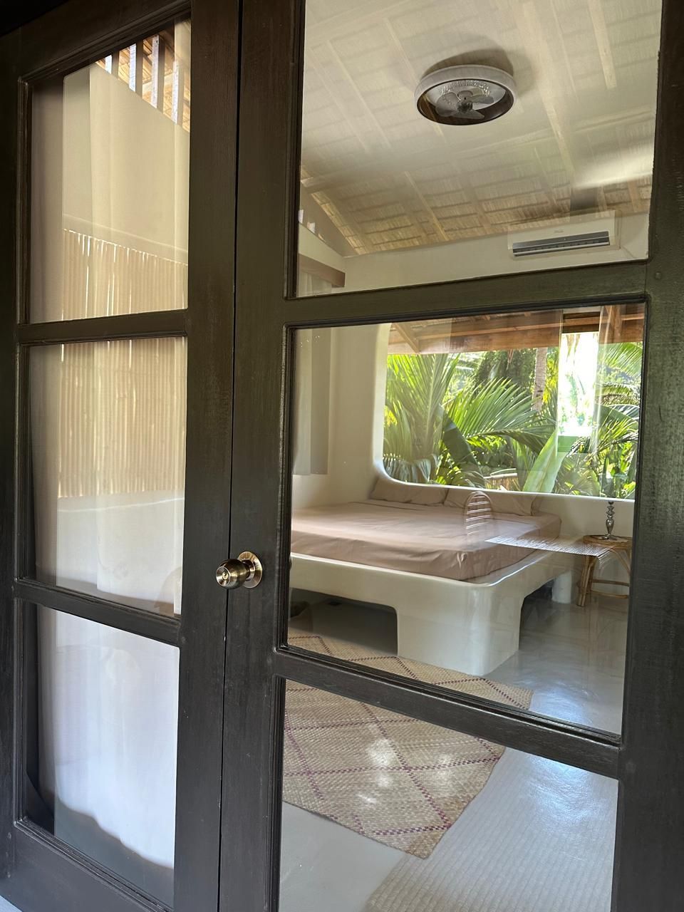 A bedroom with a bed and a window behind a glass door.