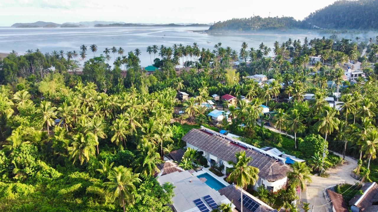 An aerial view of a resort surrounded by palm trees and a body of water.