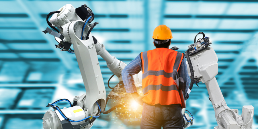 A man is working on a robotic arm in a factory.