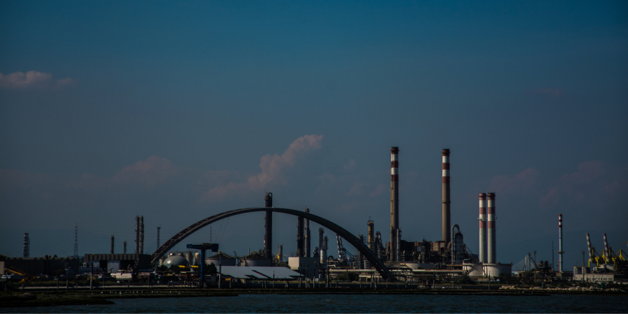 A bridge over a body of water with a factory in the background.