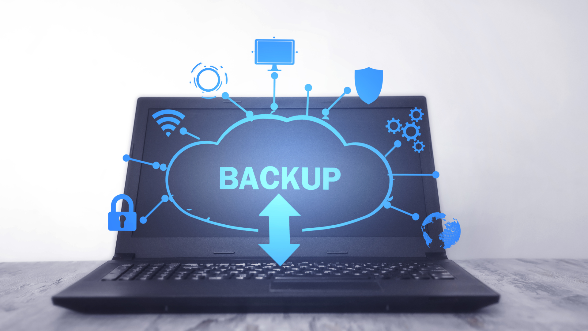 A laptop computer with a cloud and a backup icon on the screen.