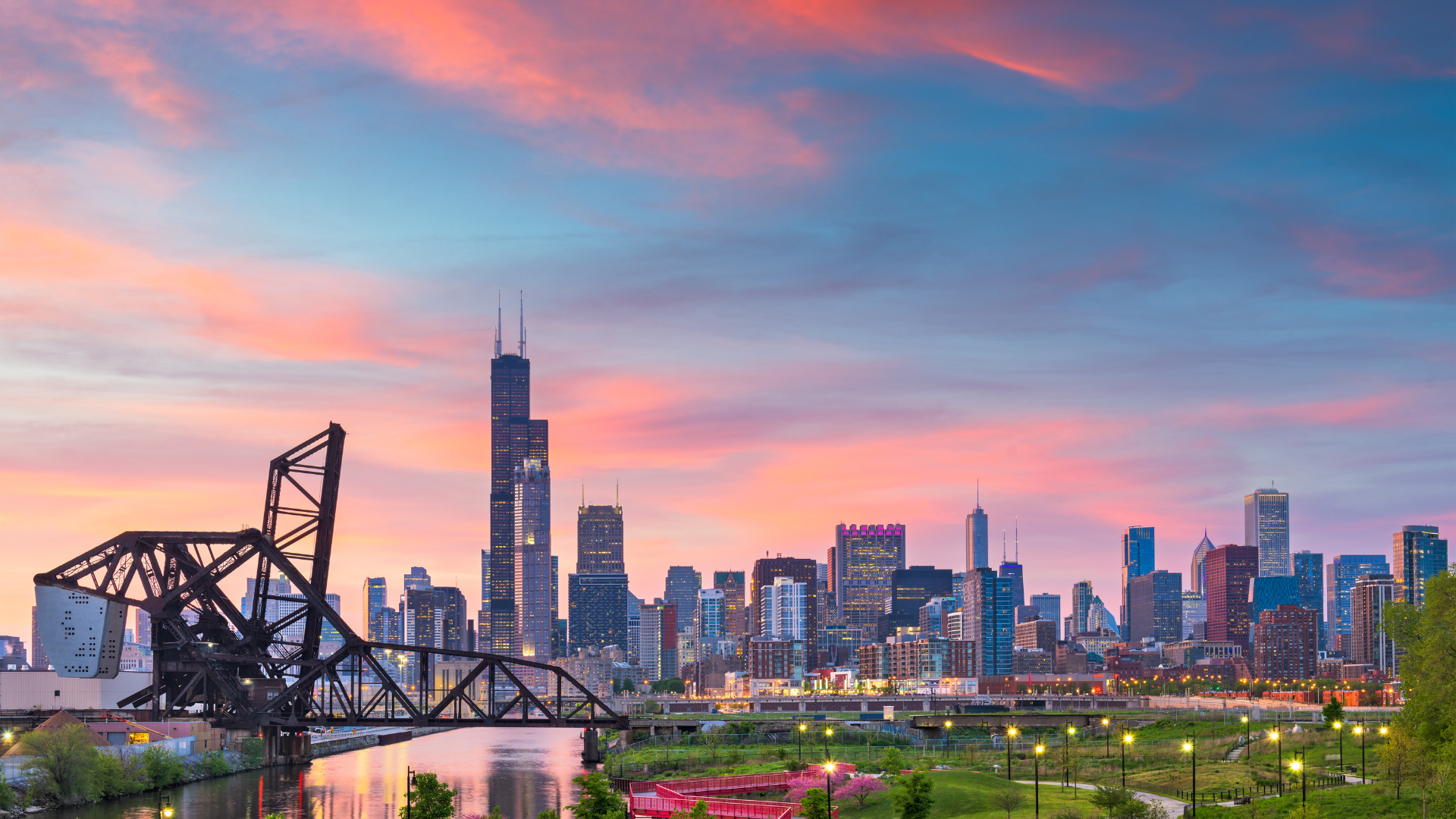 The skyline of chicago at sunset with a bridge in the foreground.
