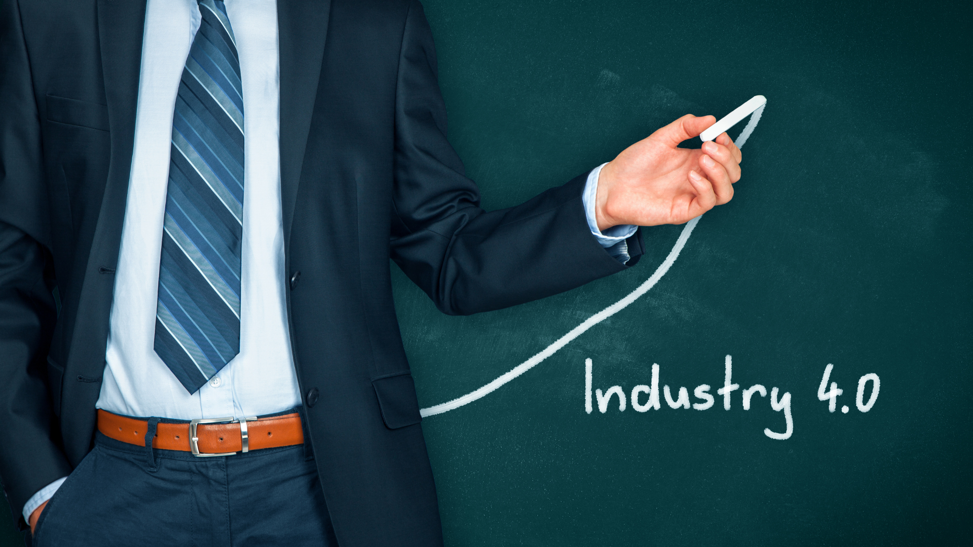 A man in a suit and tie is pointing at a chalkboard that says industry 4.0