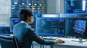 A man is sitting at a desk in front of a computer monitor.