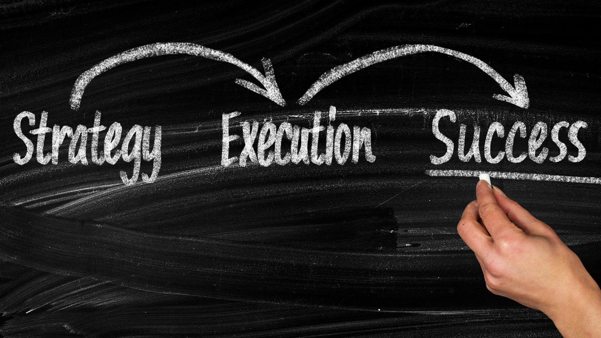A person is writing strategy execution success on a blackboard