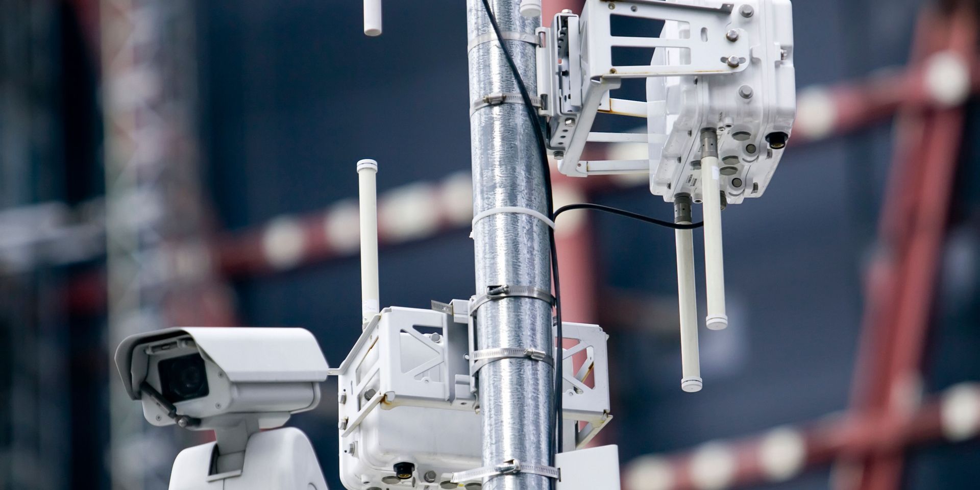 A security camera is sitting on top of a metal pole.