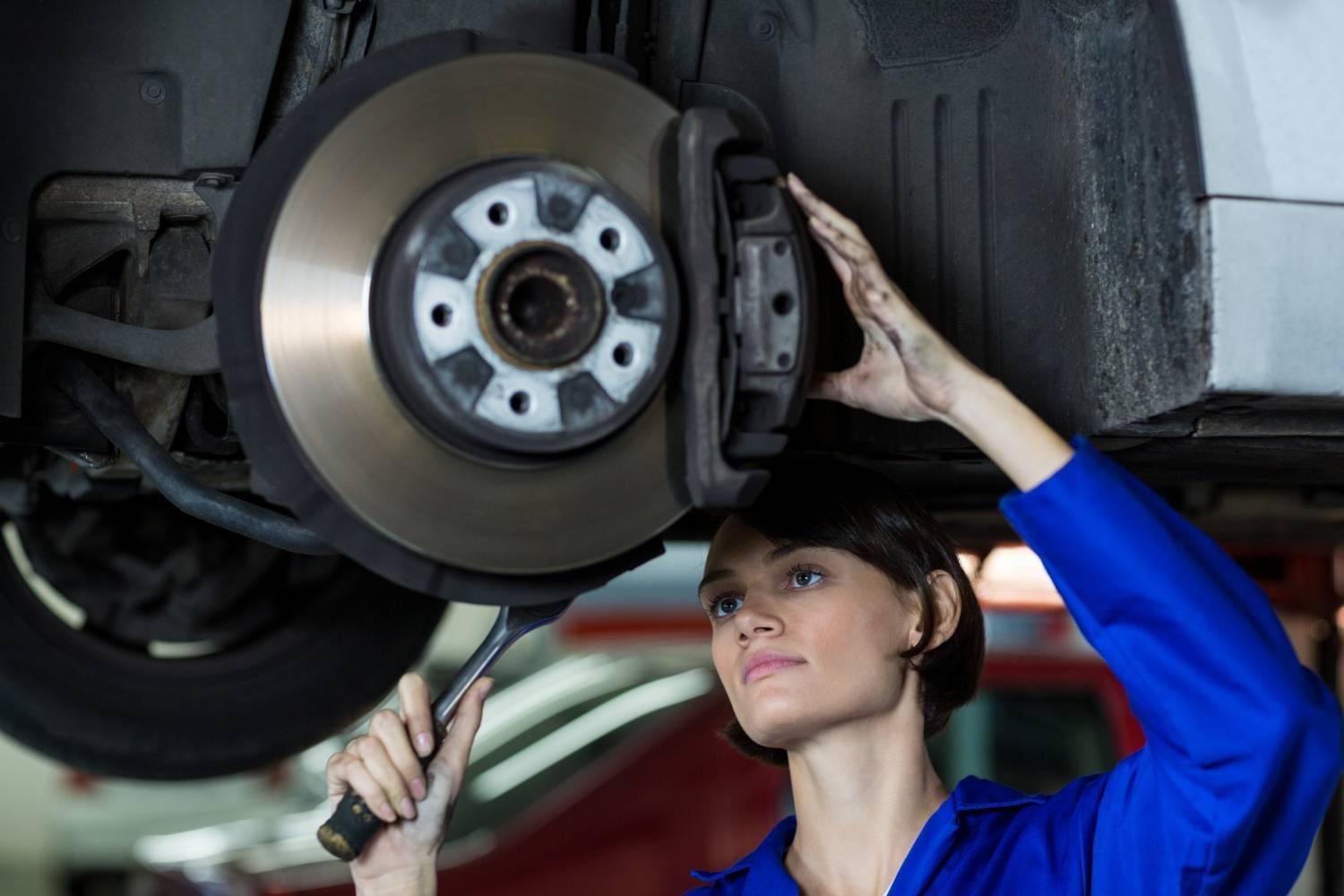Female mechanic fixing a car wheel disc brake
