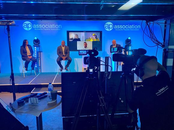 A group of people are sitting on a stage in front of a camera.