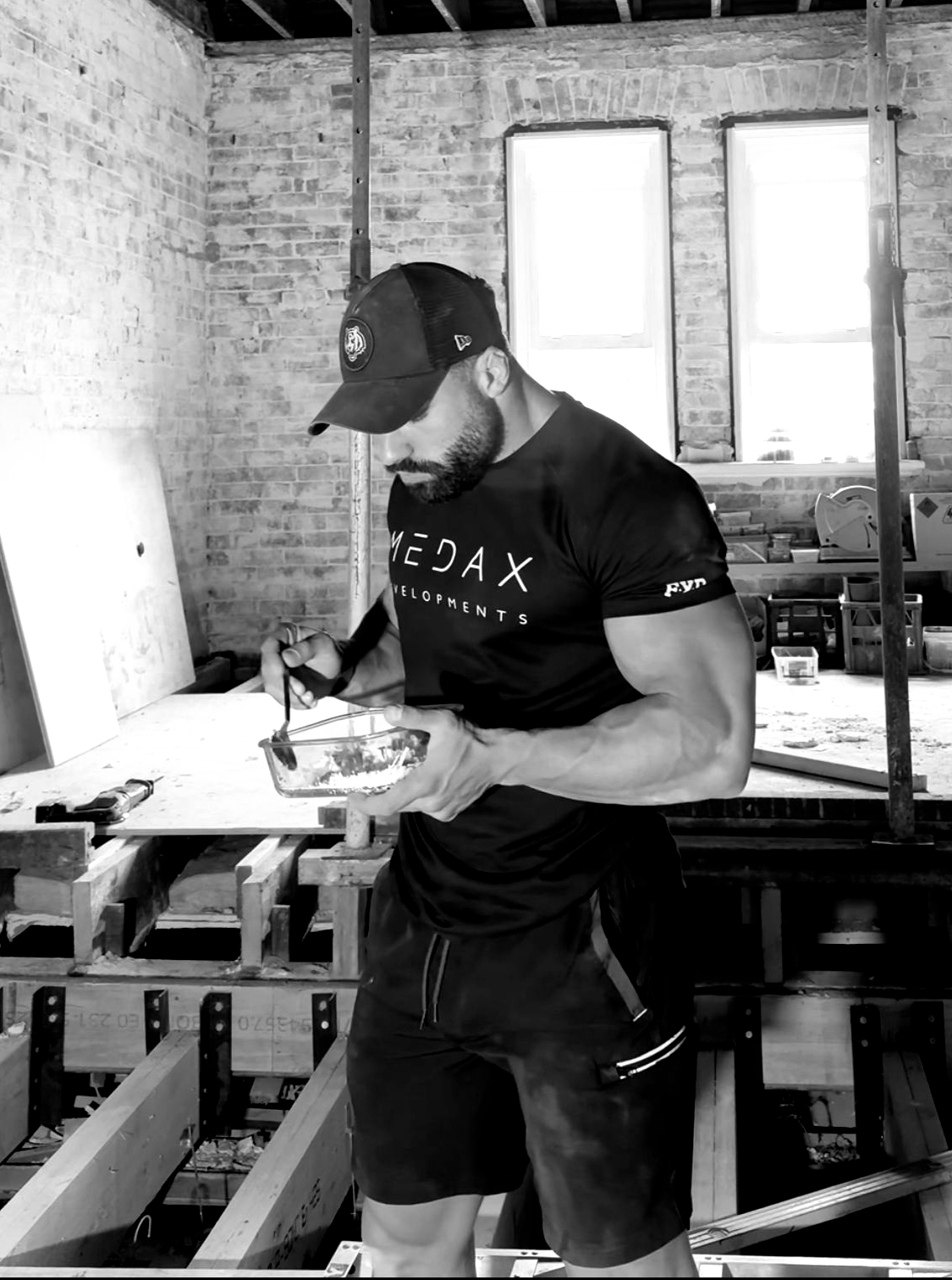 A shirtless man is sitting on a bench in a gym.