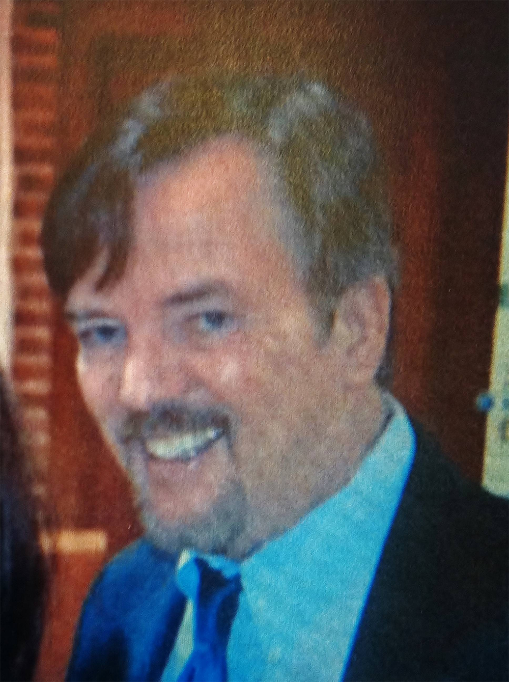A man in a suit and tie is smiling for the camera.
