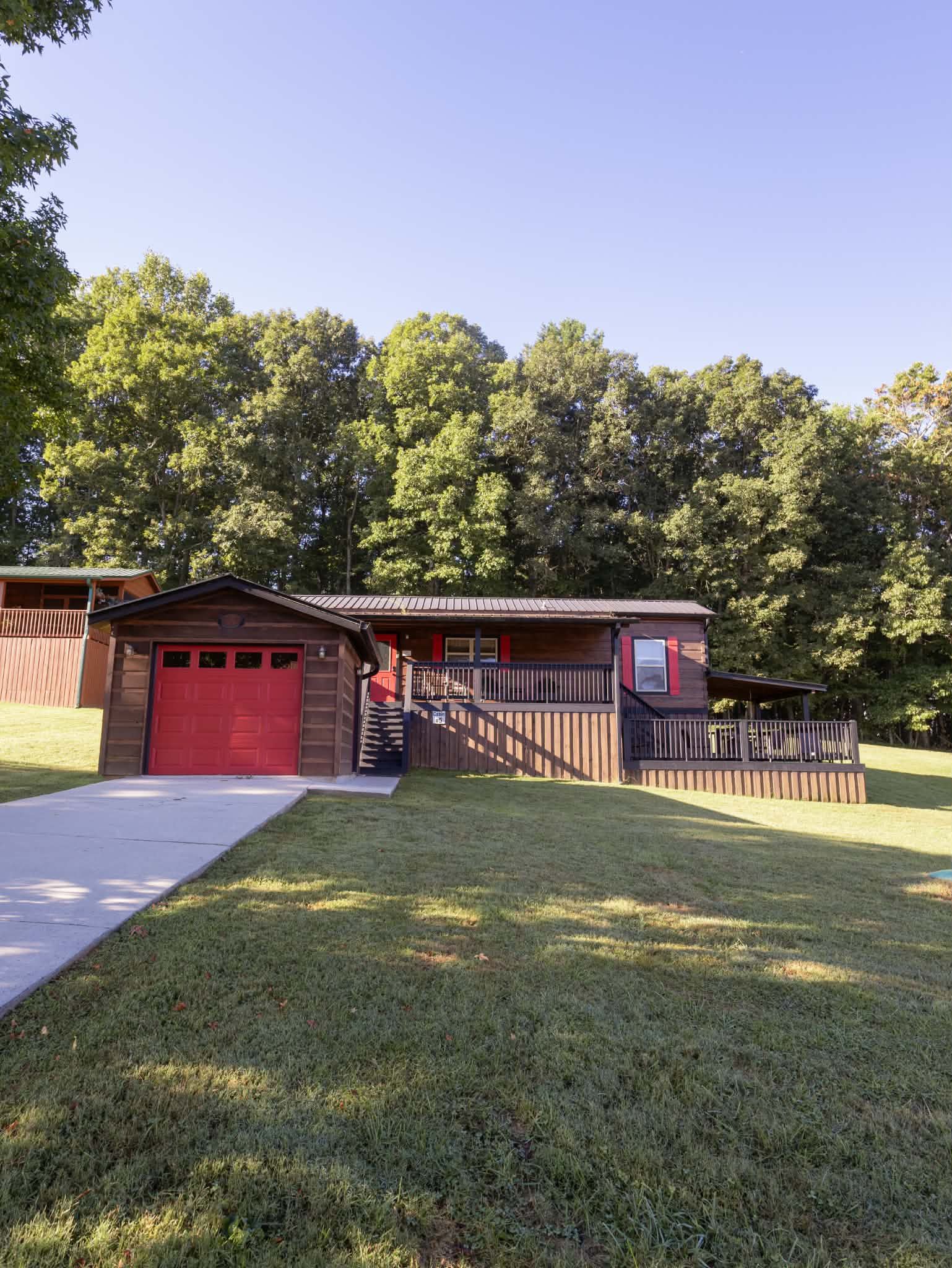 Cabin exterior with red garage door surrounded by trees