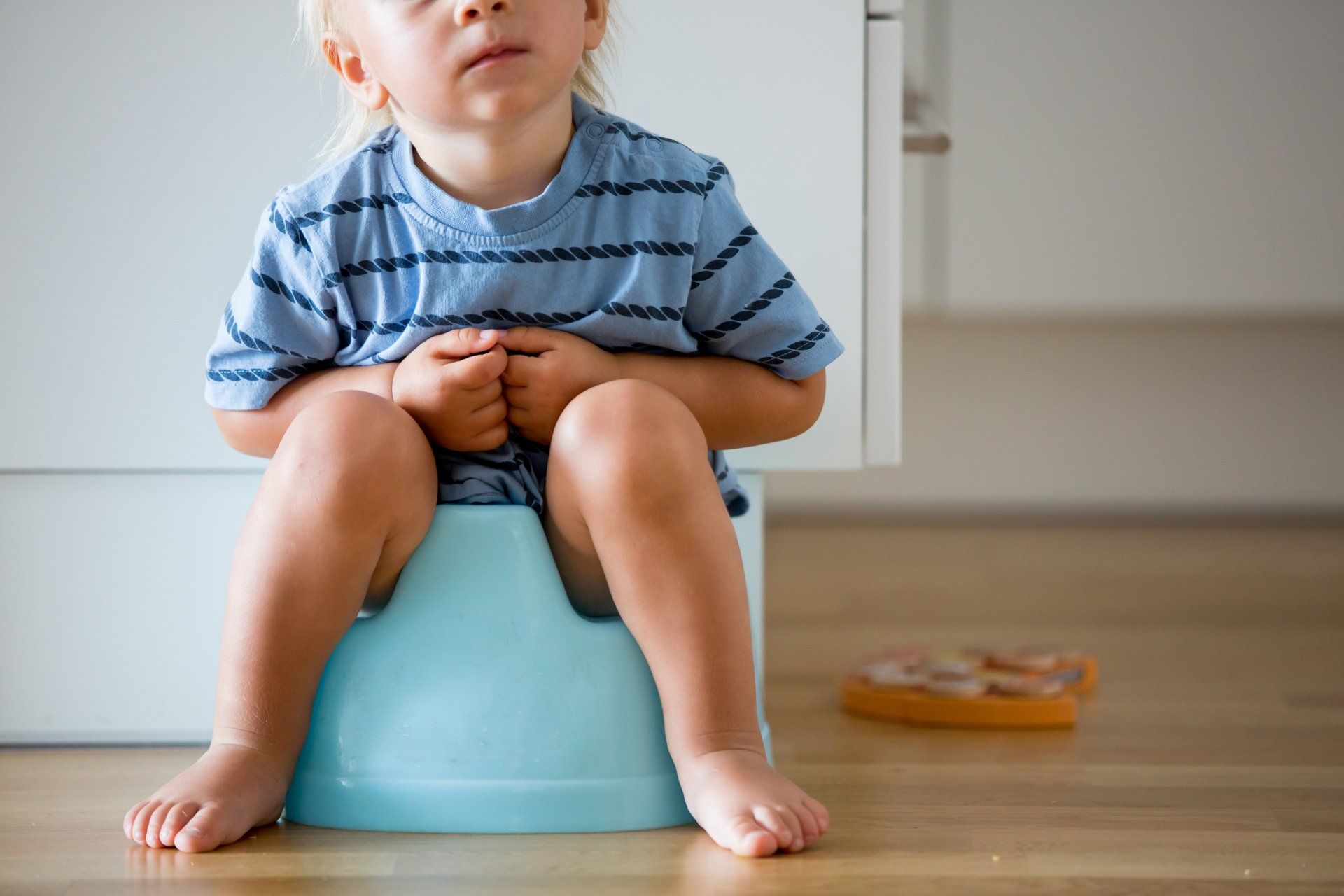 A young boy is sitting on a blue potty.