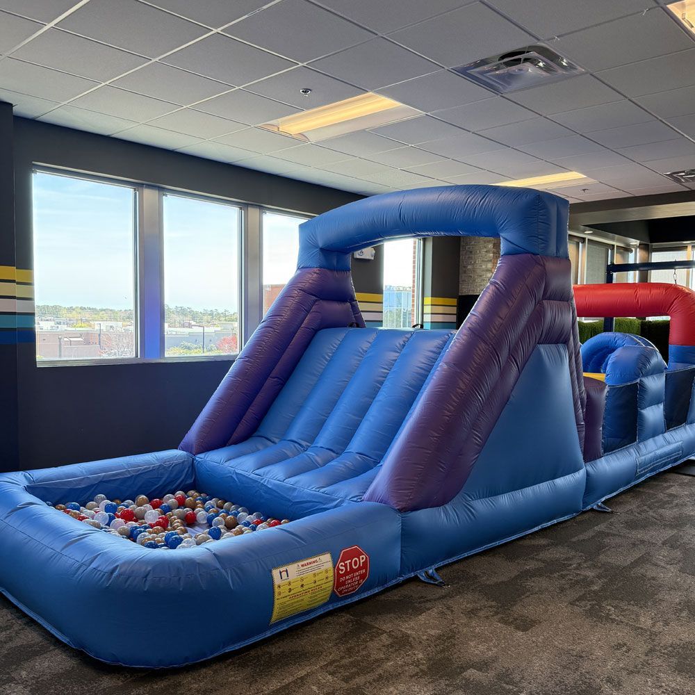 A large inflatable slide is sitting in a room next to a ball pit.