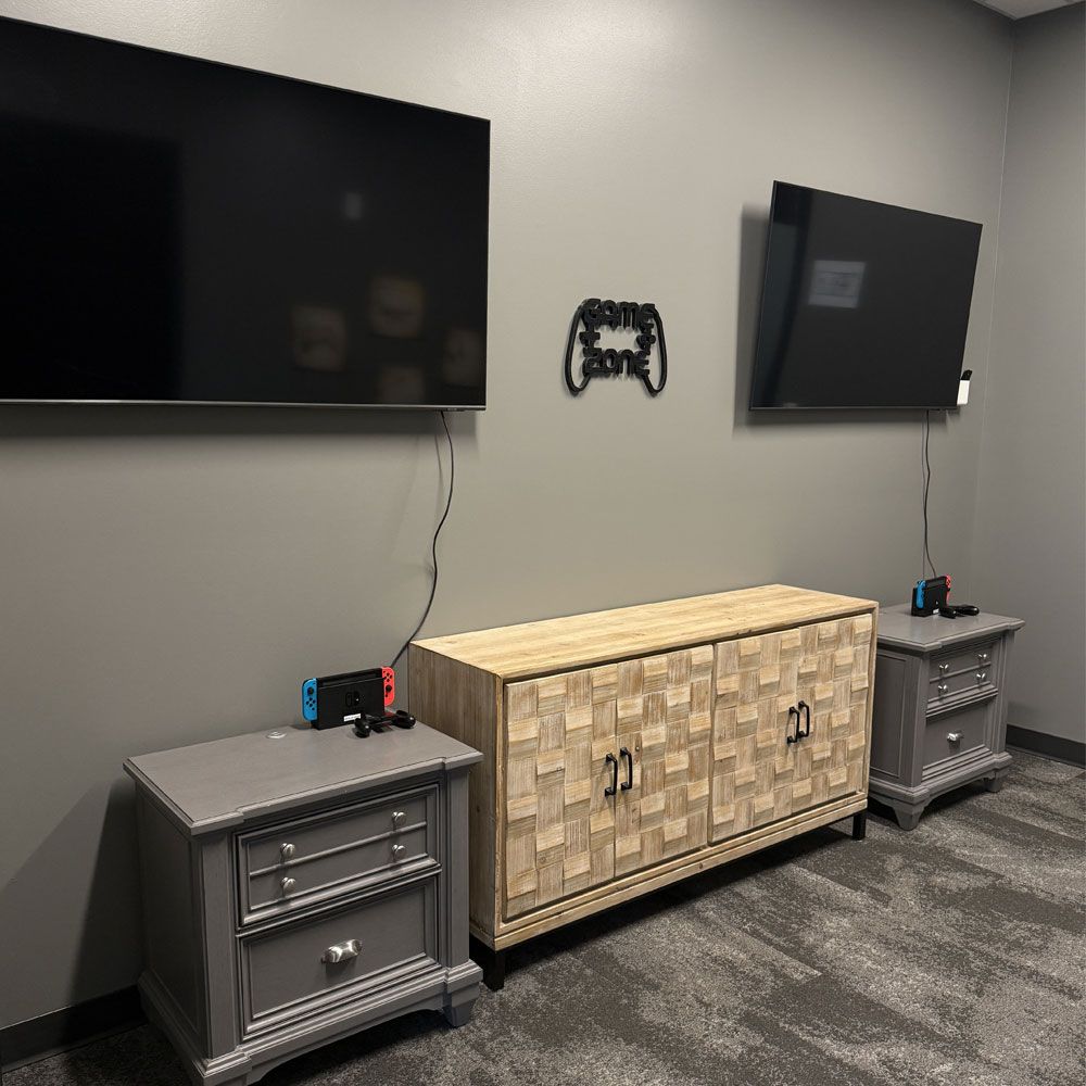 A living room with two nightstands , a television , and a nintendo switch.