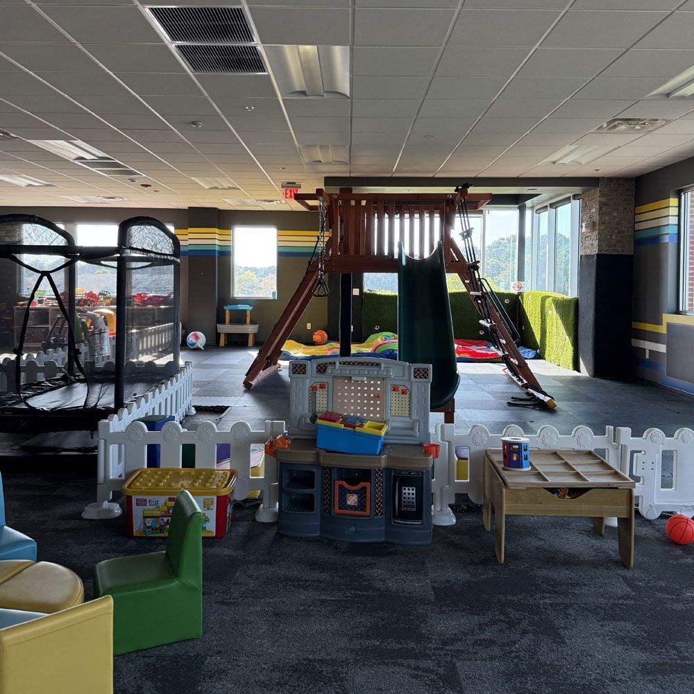 A large room with a slide and a trampoline in it