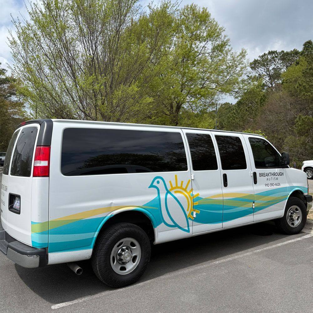 A white van with a bird on the side is parked in a parking lot.
