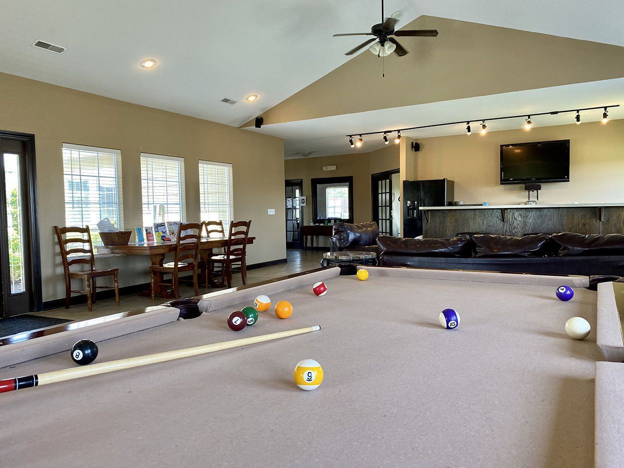 Pool table in a rec room with a dining table, couch, and black door.