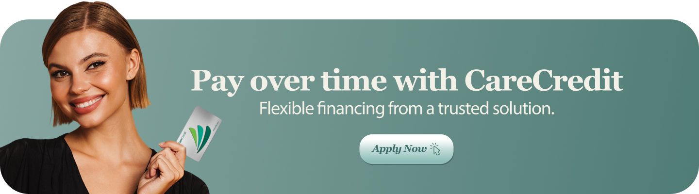 Woman holding CareCredit card, smiling. 