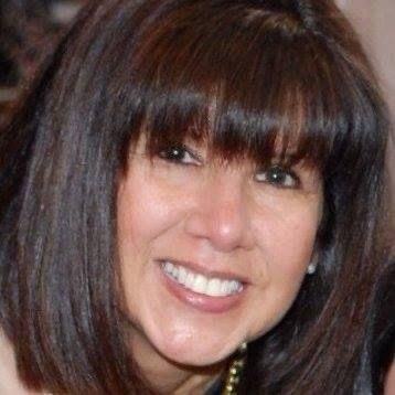 A woman with brown hair and bangs is smiling for the camera.