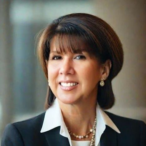 A woman with brown hair and bangs is smiling for the camera.