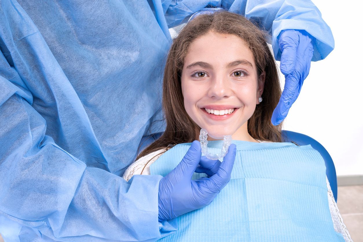 Smiling patient in blue dental bib while gloved hands prepare for a dental exam