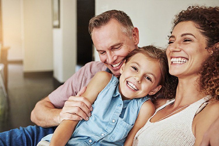 A man and woman are sitting on a couch with a little girl.