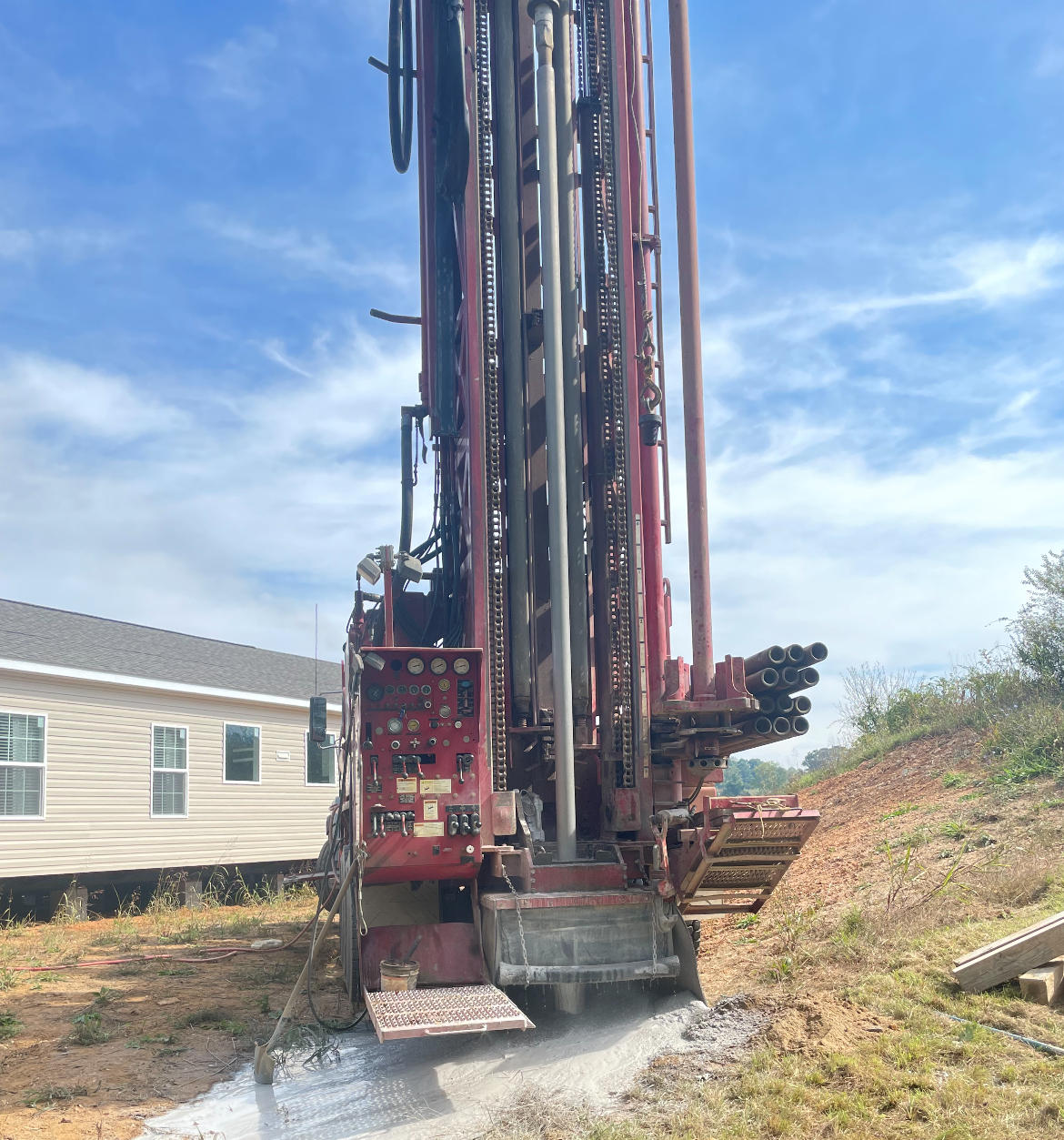 Water well drilling rig operating next to a residential property