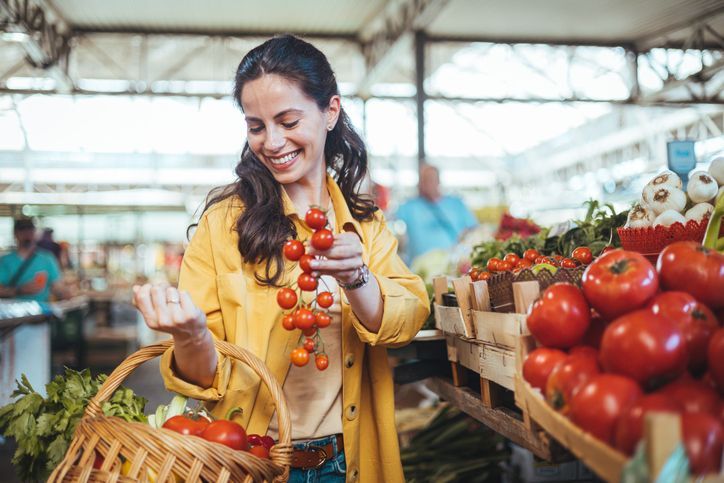 Young woman buying fresh organic produce at a local farmer's market
