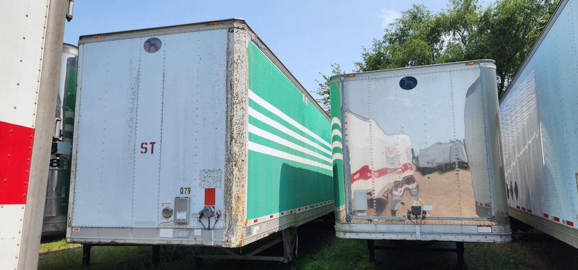 Several white and green cargo trailers parked outdoors.