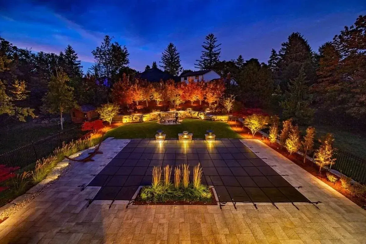 Illuminated modern courtyard with water features, trees, and warm landscape lighting at dusk