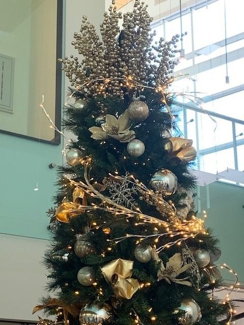 Decorated Christmas tree with silver ornaments and warm fairy lights in a bright indoor lobby