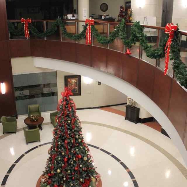 Holiday-decorated lobby with a large Christmas tree and red bows on a curved balcony