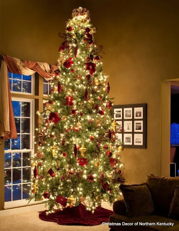 Decorated Christmas tree with white lights and red ornaments in a warmly lit living room