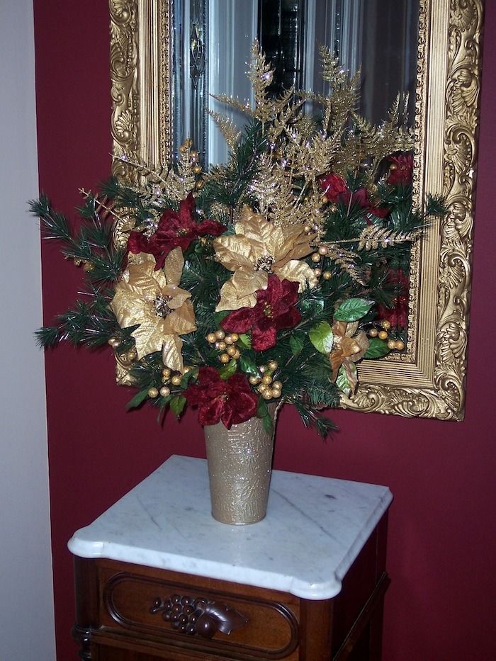 Festive floral arrangement with gold and red accents in a vase on a small table