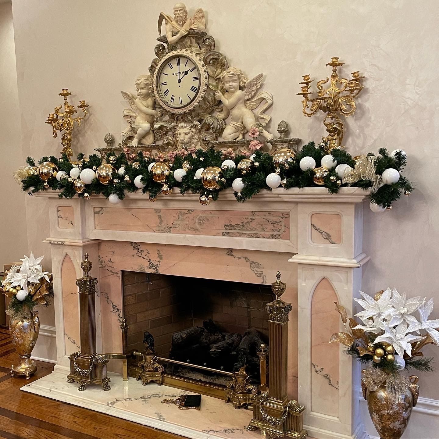 Decorated fireplace mantel with flowers, gold accents, and a clock in a formal living room