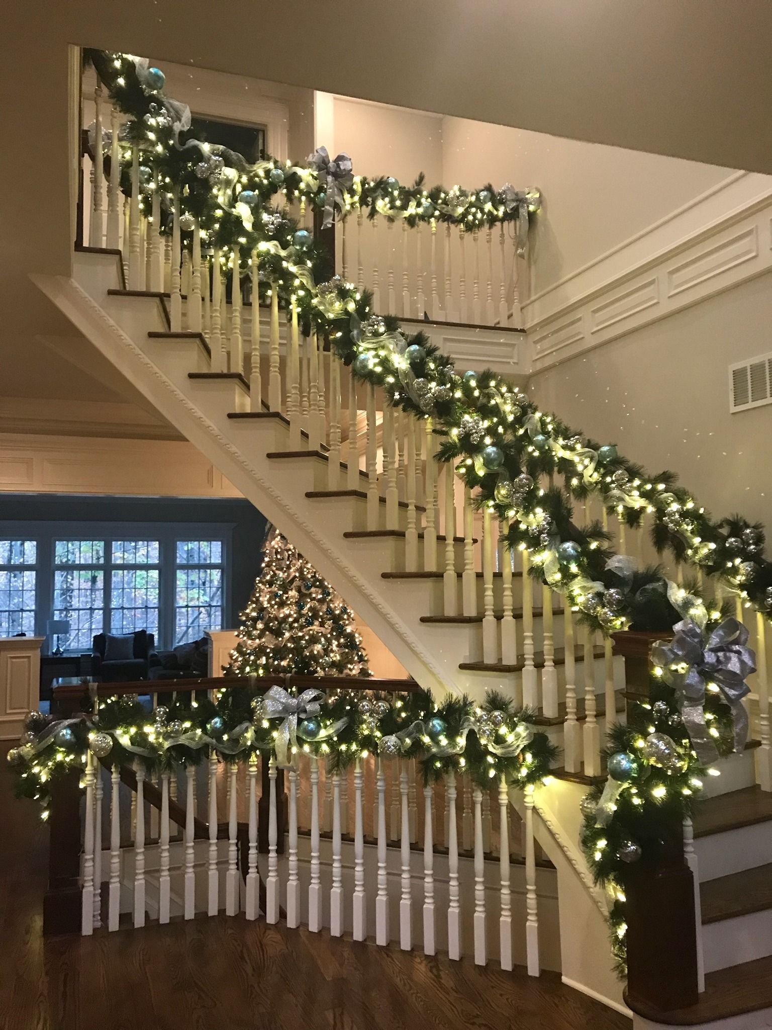 Festive staircase decorated with garland and warm white lights in a home foyer