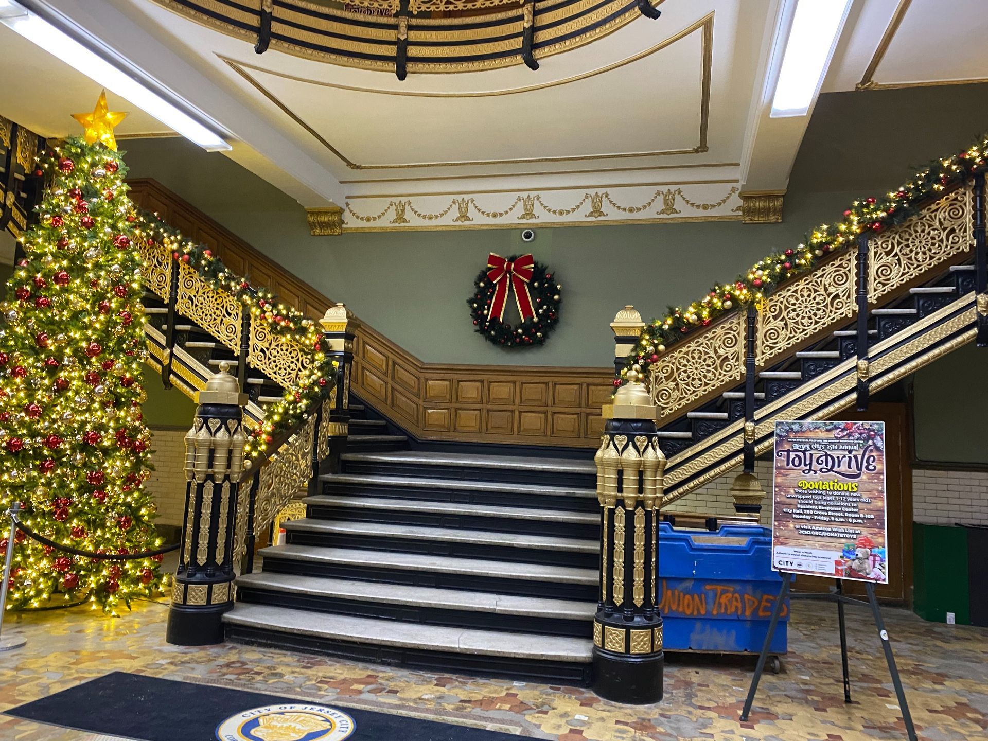 Festive lobby staircase decorated with garlands, lights, and a large Christmas tree