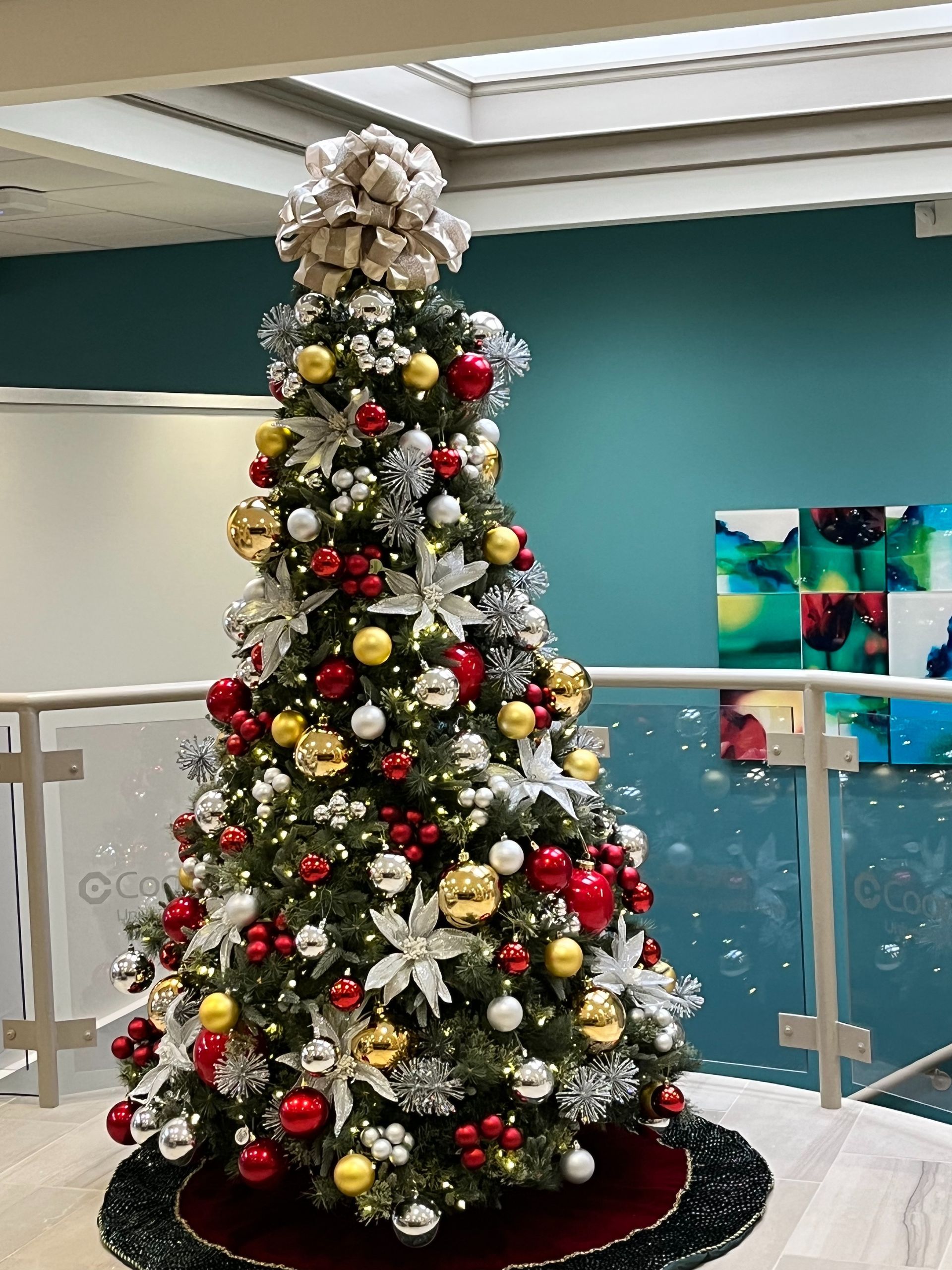 Decorated Christmas tree with red, gold, and white ornaments in an indoor lobby area
