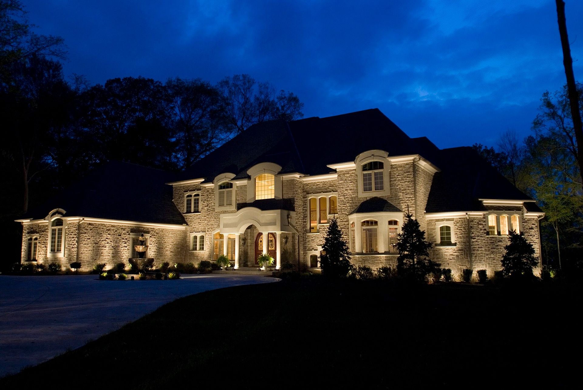 Large stone mansion lit at night against a deep blue sky