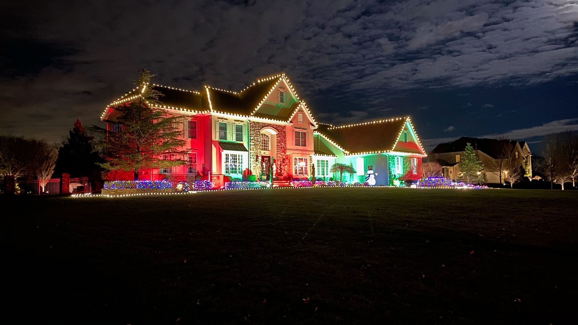 House decorated with colorful Christmas lights at night, glowing against a dark sky