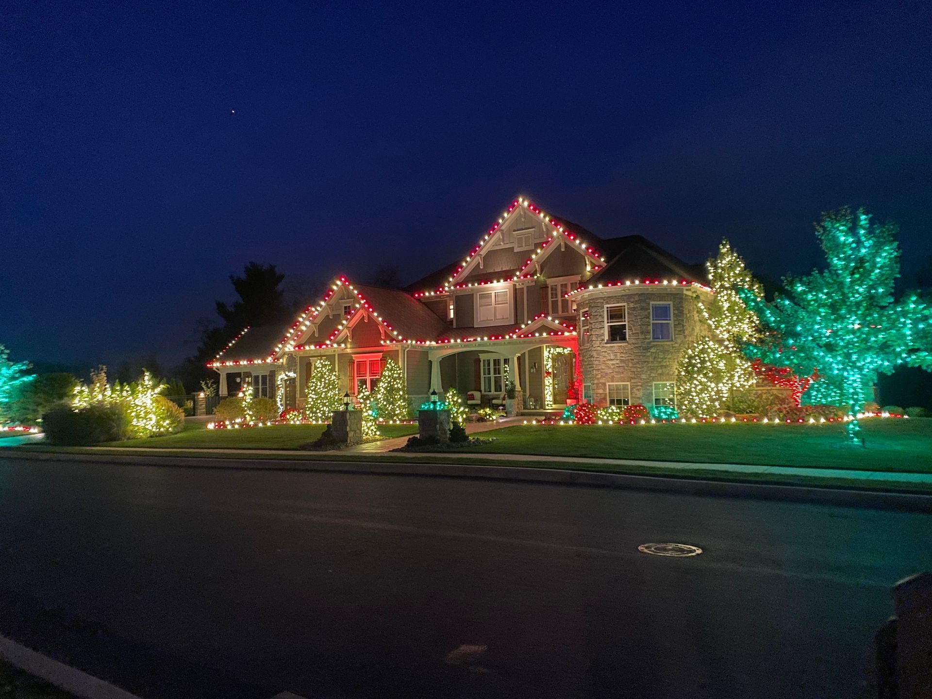 House decorated with colorful Christmas lights at night, viewed from the street